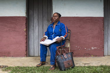 Money lender Viviane Betoko (50), who grants short-term loans to teachers at an interest rate of 50 per cent, sits with her ledger as she prepares to collect what she is owed. Civil servants in rural...