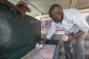 A bank employee fills metal box, inside the Land Cruiser, with cash. The bank's staff will soon leave on a two week journey to pay civil servants throughout the region.