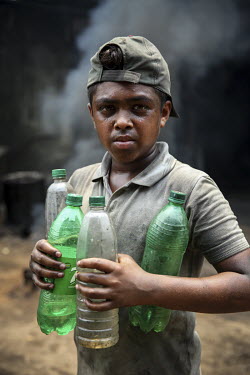 A child labourer holding bottles of water in a workshop producing parts for the ship building industry.
