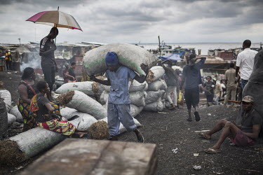 A man carries a sack of charcoal that arrived as cargo on a ship from the interior of the country. Kinshasa gobbles up charcoal, up to five million m3 a year.