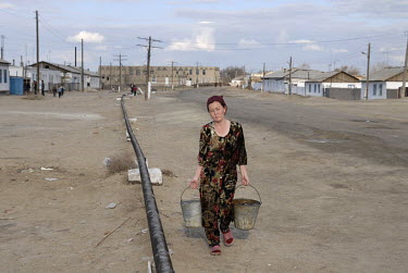 A woman carrying buckets through the former fishing town of Moynaq, a former fishing port on the Aral Sea.