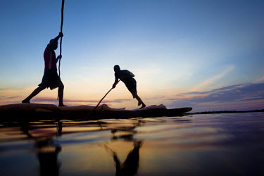 Men punt their boat from market to market along the Congo River in the hope to sell goods.