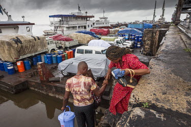 A man helps his wife climb aboard a ferry boat moored in a harbour on the Congo River. The boat will sail upstream towards Kisangani.