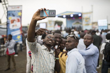 A group of youths taking joyful selfies with their mobile phones during the Amani Music Festival, a festival that promotes peace in the region.