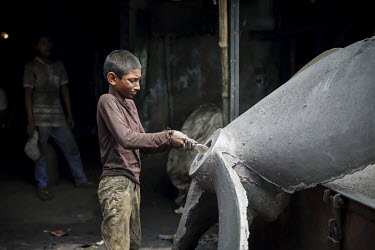 A child labourer finishes a newly cast propellor in a workshop producing parts for the ship building industry.