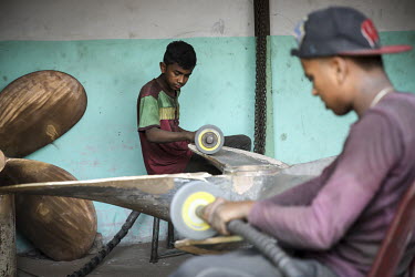 Child labourers using angle grinders to burnish metal from a newly cast propellor in a workshop producing parts for the ship building industry. The boys have no visible protective equipment.
