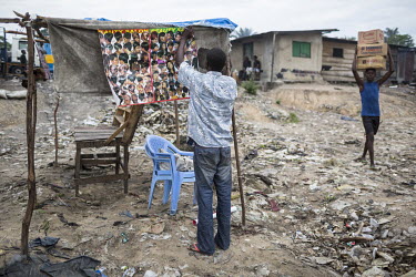 A man sets up a makeshift beauty salon on a rubbish strewn patch of land near the port.