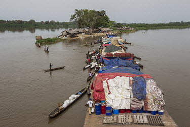 As a flotilla of barges sails up the Congo River, people from the various settlements it passes paddle their canoes (pirogues) out to the vessels in order to sell local produce to the passengers and c...