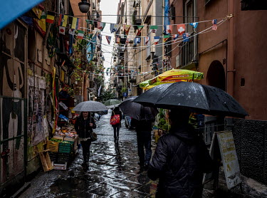 Pedestrians protect themselves with umbrellas against the steady rainfall in a small street in the Spagnoli neighbourhood.