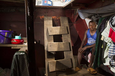 Freddy, a member of crew sitting in his makeshift cabin onboard the M/M Ma'ungano, a barge that plys the Congo River. Freddy is responsible for the inventory of goods the ship is carrying.