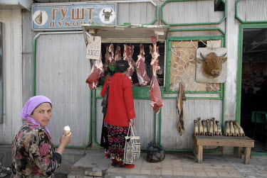 A woman examines the meat being sold at a butcher's shop.