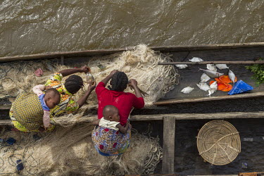 A fisherman's wife moors her canoe (pirogue) alongside a flotilla of barges travelling up the River Congo in the hope of selling their catch to the passengers or crew.