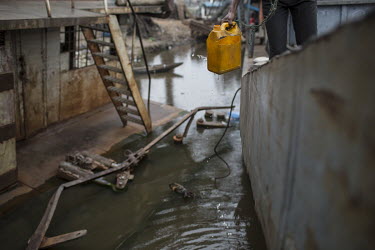 A man collects drinking water from the Congo River in a harbour littered with disused and unfinished vessels. Such wrecks often hamper navigation on the river while others are home to squatters or hom...