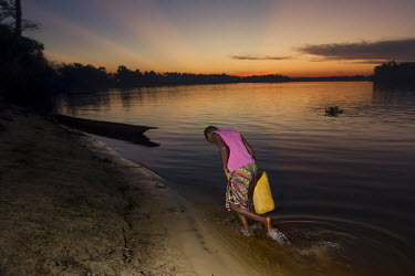 A dusk, a young woman fetches water from the Lomami River. The consumption of contaminated water is often the cause of cholera outbreaks along the river.