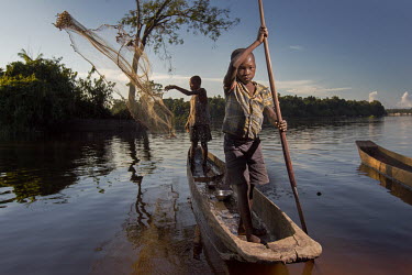 While his companion steers the boat, a young boy casts his net. Part of any catch is sold. The remaining fish are used to feed the family.