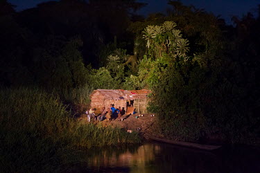 A family and their simple dwelling is illuminated by the powerful searchlight of a barge travelling up the Congo River. When dusk falls, crew members on vessels travelling on the river scour the banks...