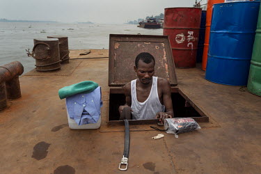 A 'convoyeur' or ship's mate, working aboard a Congo River barge, prepares to dress for the day.