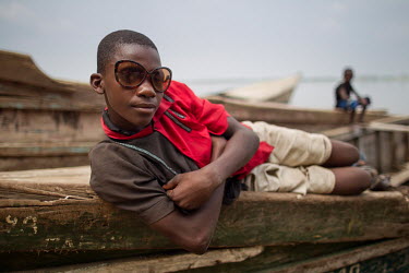 A youth lies on a canoe (pirogue) moored on the banks of the River Congo.