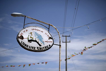 An old sign with the slogan 'long live Eritrea' hangs from a lamp post.