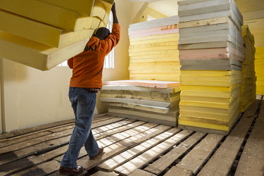 A worker in a factory manufacturing foam mattresses.