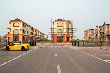 A lone Lamborghini stands in front of new apartment buildings under construction at the 'Cite du Fleuve' gated community. The development was built by a Chinese developer on an artificial peninsula in...