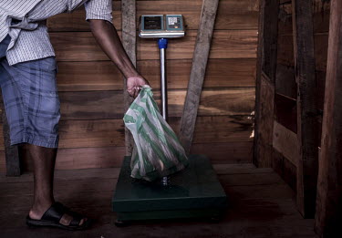 A street trader weighs a bag of vanilla pods.