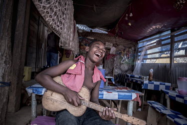 A boy plays a home-made guitar in a small restaurant owned by a vanilla farmer in the village of Belambo.
