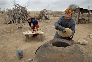 Two women baking bread in a 'tamdyr', a traditional clay oven, in the desert village of Kekirdek.