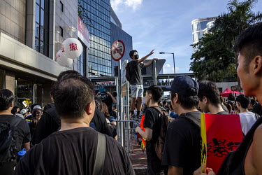 A man climbs scaffold to make a point as a huge crowd, mostly dressed in black, made itw way from Victoria Park to Central during a mass demonstration against the extradition bill, police use of force...