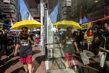 A protestor, dressed in black and carrying a yellow umbrella, is reflected in a shop window as demonstrators gathered to condemn the extradition bill, police use of force during protests and to demand...