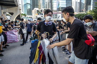 An activist hands out umbrellas to protestors gathering to protest against the extradition bill, police use of force during protests and to demand Chief Executive Carrie Lam's resignation.