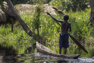 A boy travelling back home in his canoe (pirogue) on the Congo River.