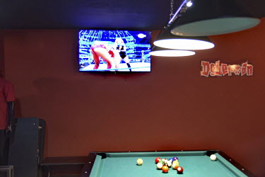 A television broadcasts a women's wrestling match in a pool hall.