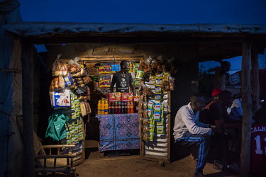 Kennedy Lemmy (22), a South Sudanese refugee, waits for customers in his shop where he sells bread, snacks, nappies and other basic items. Ugandan government policies mean that refugees are able to wo...