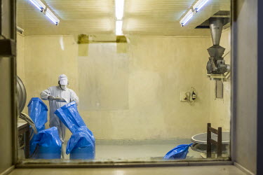 A man working in a sterile lab at a Papain producer fills sacks with powdered Papain. Papain is present in papaya and is produced from the latex of the papaya fruit which is collected by making insici...