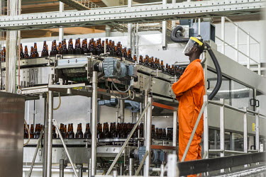 A worker checks bottles of beer as they pass him on the assembly line in a Brasimba brewery. Brasimba, owned by the Castel company, opened the facility in 2012. It mainly produces Tembo and Simba bran...