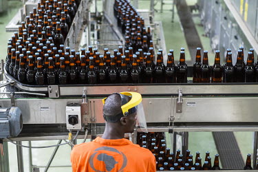 A worker checks bottles of beer as they pass him on the assembly line in a Brasimba brewery. Brasimba, owned by the Castel company, opened the facility in 2012. It mainly produces Tembo and Simba bran...