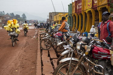 Moto-taxis waiting for passengers beside an unpaved road in the town centre.