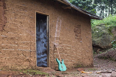 A homemade guitar standing outside a house.