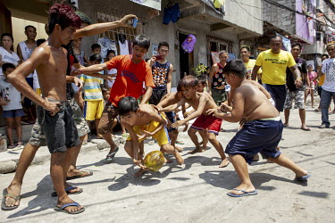 Children playing a version of rugby in the street using a fresh coconut as a ball.