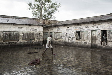 An inmate walking in the rain across the prison courtyard.