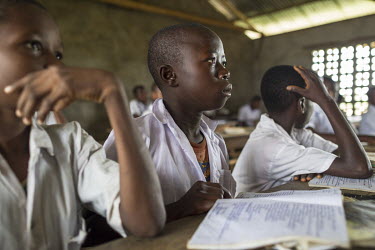 Boys sit at their desks in a classroom with their notebooks open in front of them.