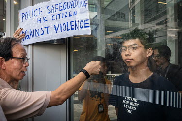 A pro-establishment demonstrator outside the Legislative Council building shouts through window at activist Joshua Wong (right) looks out at his political opponents as protests against the government'...