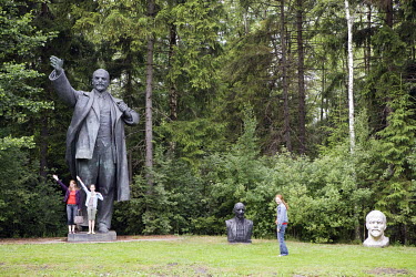 Visitors copy the pose of a giant Lenin statue in Grutas Park. The sculpture garden of Soviet-era statues and displays of other ideological relics, was founded by the Lithuanian entrepreneur Viliumas...