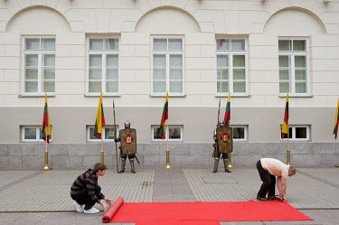 A red carpet is rolled out in front of the presidential palace in the city centre, for an official speech on the anniversary of the crowning of King Mindaugas. The guards near the national flag wear h...