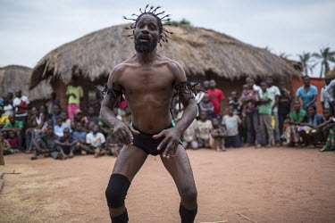 A wrestler performs his pre-fight rituals in front of an eager crowd of spectators outside the ring. He is part of a travelling troupe of fighters who go from village to village putting on a show for...