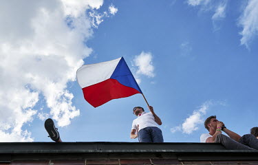 A man waves a Czech flag from a roof overlooking a rally in Letna Park where a crowd of a quarter of a million people, the biggest protest since the communist era, gathered to demand the resignation o...