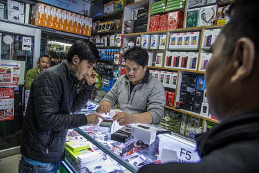 Nawang Shisp, owner of Tsering Electronics a phone and electronics store in Leh's central market, shows mobile phones to a customer .