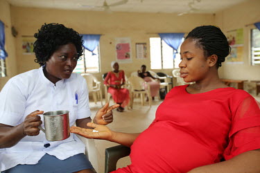Omogo Chinelo Ruth, who is a pregnant, is given sulfadoxine pyrimethamine, a malaria treatment, by nurse Ani Chidiebere before her antenatal care programme at the Ngbo Primary Health Care Clinic.
