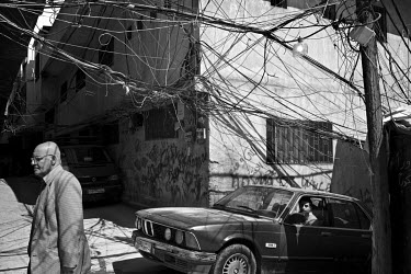 A tangle of power cables and a man walking in Beddawi Palestinian refugee camp.